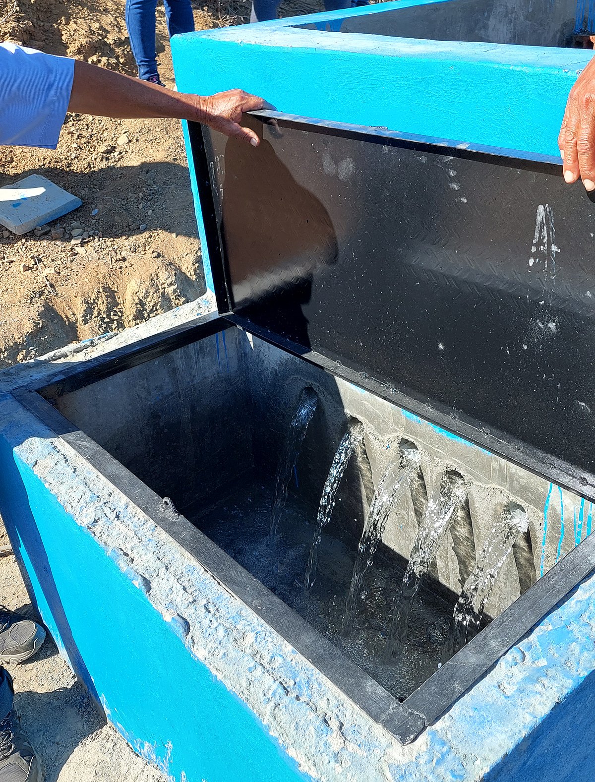 Wasser fließt aus einem Brunnen aus Beton.
